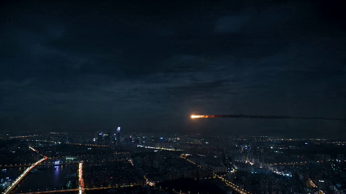 A glowing asteroid enters the atmosphere above a sprawling metropolis at